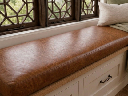 A brown leather window seat cushion installed on a wooden storage bench with cream drawers, positioned beneath a dark wood lattice window.
